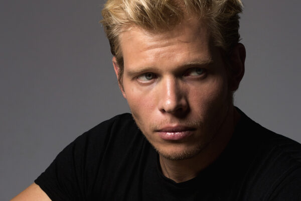 Headshot of actor Daniel Horvath, showcasing his expressive features. He has neatly styled dark hair, a slight smile, and is dressed in a casual shirt. The soft lighting and neutral background emphasize his approachable and charismatic presence, making him stand out as a dynamic performer